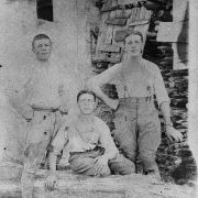 219 - Gruppo di 3 uomini. Sullo sfondo una legnaia